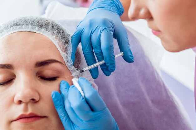 De arts-schoonheidsspecialist maakt een procedure voor gezichtsinjecties.