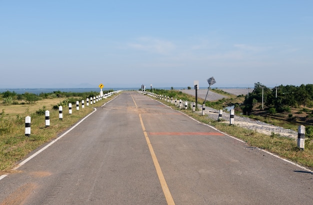 De asfaltweg van de landelijke weg is in de zomer gebogen langs het reservoir van de grote dam, vooraanzicht met de kopieerruimte.