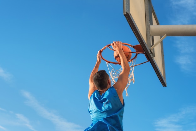 De atleet die van het straatbasketbal slag uitvoert dompelt op het hof onder