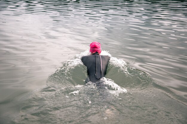 De atleet duikt het water in in een wetsuit