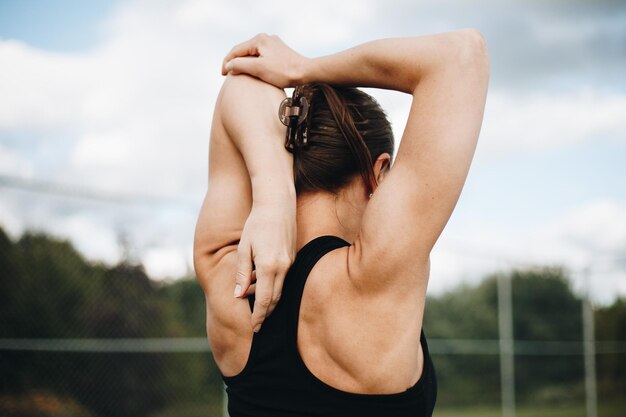 Foto de atleet warmt op voor de training. trainen in de avond. de vrouw staat erachter.