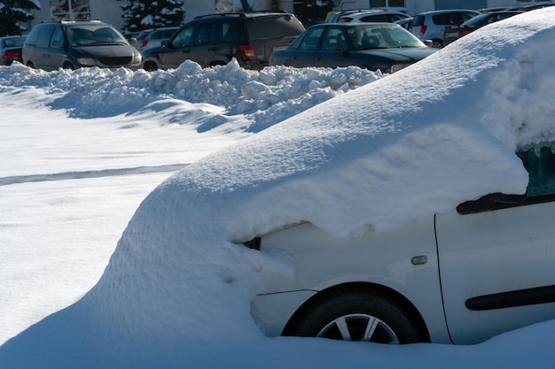 De auto op de parkeerplaats is volledig bedekt met sneeuw Problemen na hevige sneeuwval Grote sneeuwbanken op de parkeerplaats en op de wegen