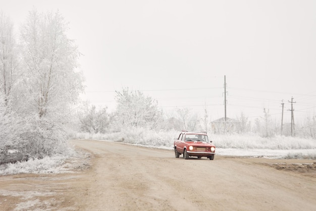 De auto rijdt over een besneeuwde dorpsweg