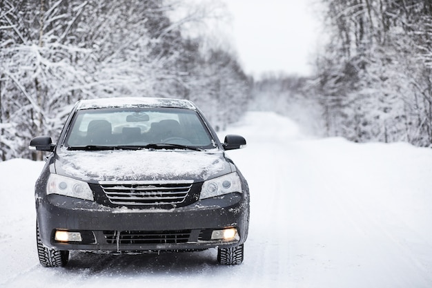 De auto staat op een besneeuwde weg in een winterse bewolkte dag