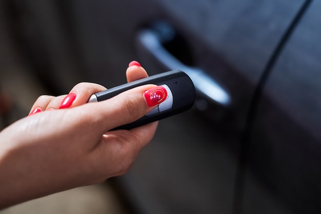 De autobezitter houdt een afstandsbediening voor keyless entry in zijn hand