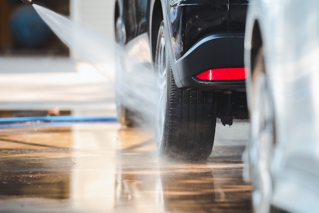 De autowasserette wast de auto met water. spuit water op wielen, reinig auto's bij wasstation