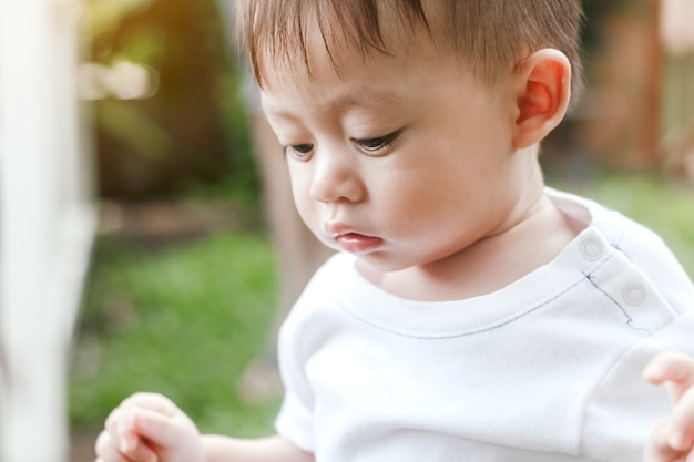 De aziatische babyjongen kijkt ergens in het park