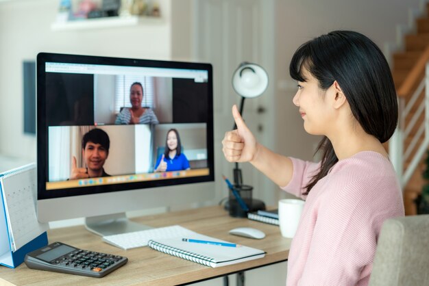 De aziatische bedrijfsvrouw beduimelt omhoog aan haar collega's over plan in videoconferentie