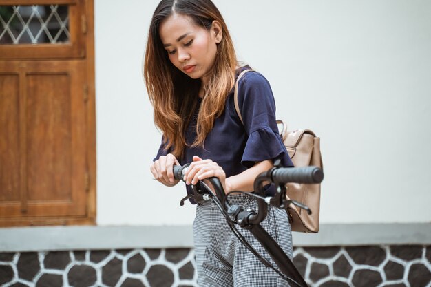 De Aziatische jonge vrouw die vouwen proberen haar vouwende fiets voor te bereiden gaat werken
