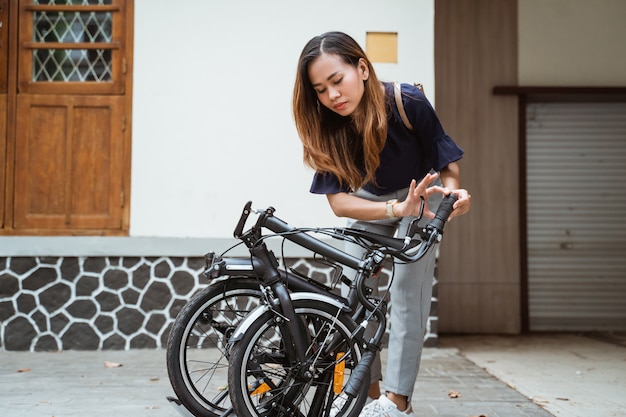 De Aziatische jonge vrouw die vouwen proberen haar vouwende fiets voor te bereiden gaat werken