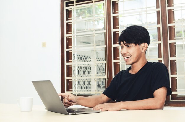 De Aziatische man zat naar de laptop te wijzen