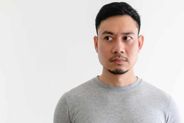 De Aziatische mens in een grijs t-shirt bekijkt geïsoleerde kant