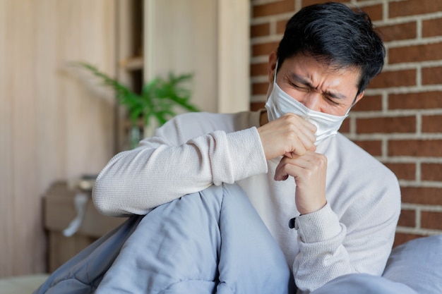 De Aziatische mens wordt wakker en hoest in slaapkamer (quarantainegebied) voor coronavirus preventief