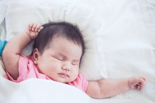 De Aziatische pasgeboren slaap van het babymeisje op wit bed