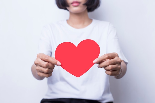 De Aziatische vrouw in witte kleding toont hartvorm in het concept liefde en valentijnskaart