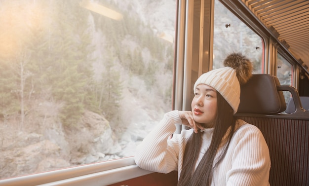 De Aziatische vrouw kijkt natuurlijk mening vanuit het venster op de trein