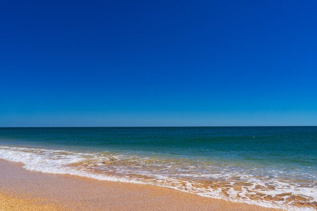 De azuurblauwe zee met geel zand van schelpen