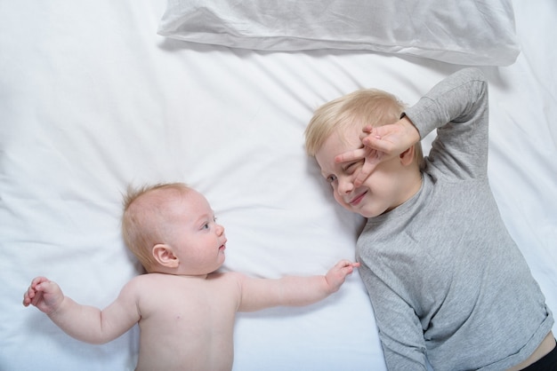 De baby en de glimlachende oudere broer liggen op het bed