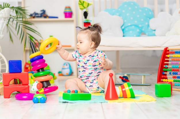 De baby haalt de piramide op, het kind speelt thuis in de crèche