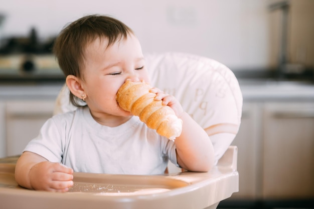 De baby in de keuken eet gretig heerlijke romige tubes gevuld met vanilleroom