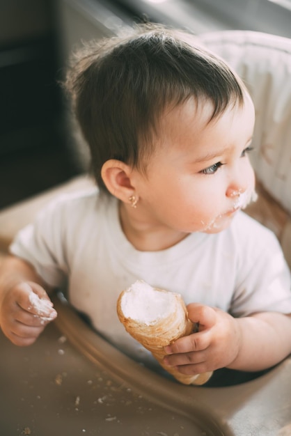 De baby in de keuken eet gretig heerlijke romige tubes gevuld met vanilleroom