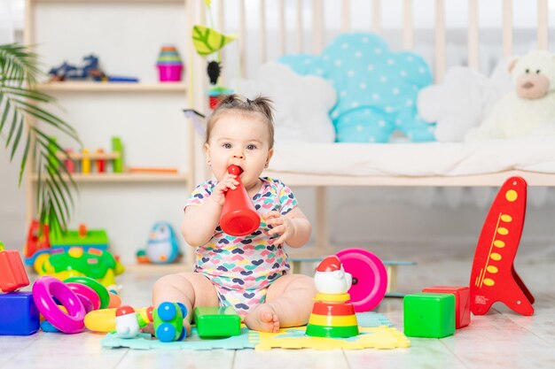 De baby knabbelt aan speelgoed het kind speelt thuis in de kinderkamer Speelgoed voor kleine kinderen