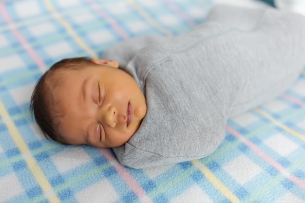 De baby ligt in een cocon op het bedje. Hij slaapt lief en droomt