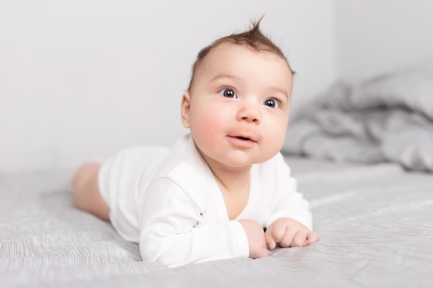 De baby ligt op zijn buik op het bed Een mooie baby glimlacht Mockup voor ansichtkaarten voor reclameontwerpviering