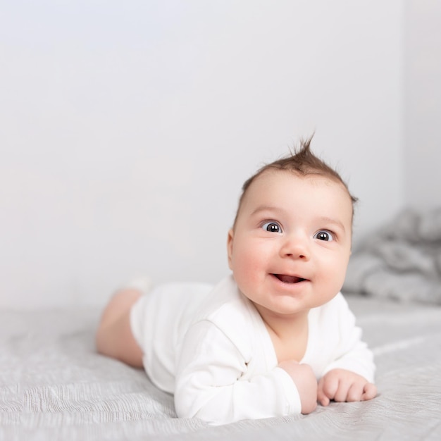 De baby ligt op zijn buik op het bed Een mooie baby glimlacht Mockup voor ansichtkaarten voor reclameontwerpviering