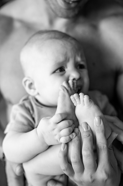 De baby wordt vastgehouden door zijn vader en zijn voeten worden getikt door de tenen van de baby.