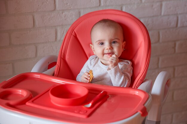 De baby zit in een hoge stoel te eten