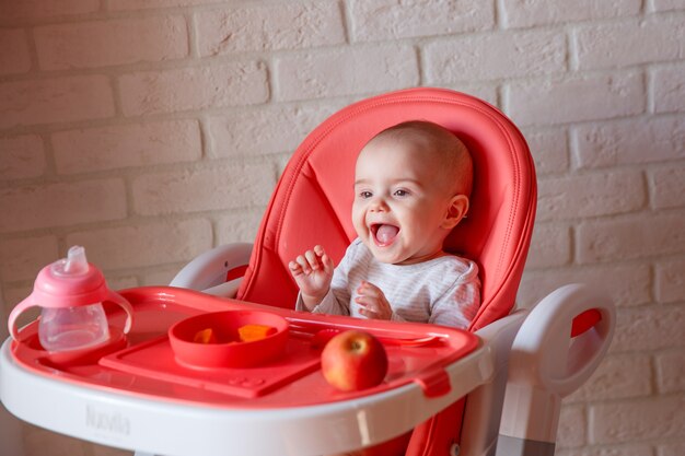 De baby zit in een hoge stoel te eten