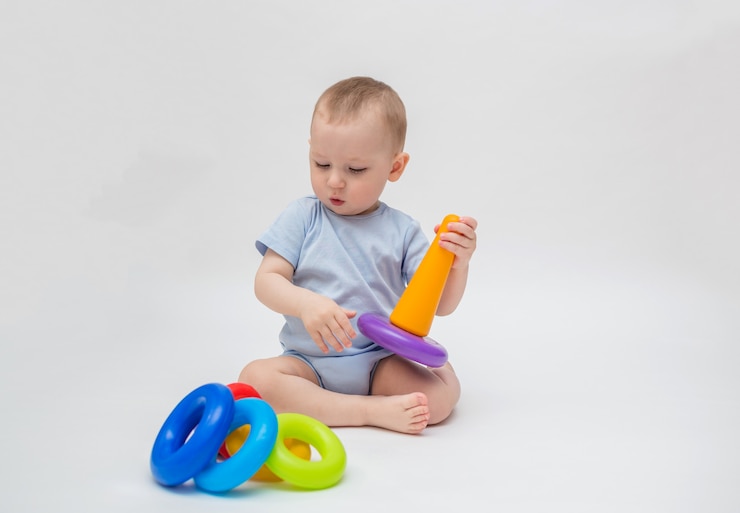 Foto de babyjongen op een witte achtergrond speelt in de piramide