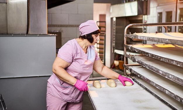 De bakker vormt het deeg voor het bakken van brood en legt het in de ovenschaal bij de productie