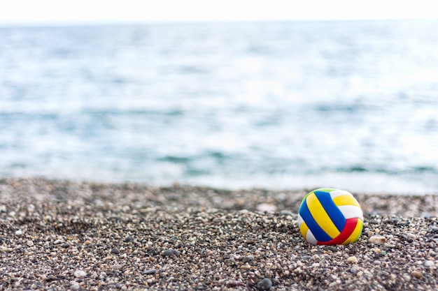 De bal van gekleurde eenzame kinderen op een pabble strand op zomer zee achtergrond.