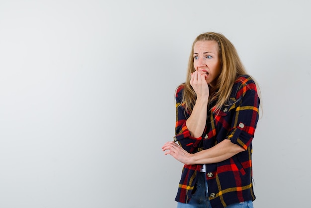 De bange vrouw kauwt haar nagels op een witte achtergrond