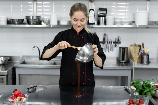 De banketbakker schenkt warme chocolademelk op een koude tafel om te temperen.