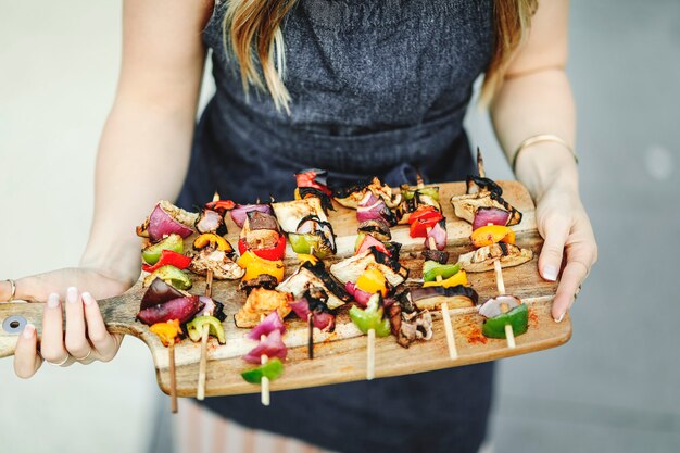 De barbecuespitpannen van de vrouwen dienende veganist op een houten raad