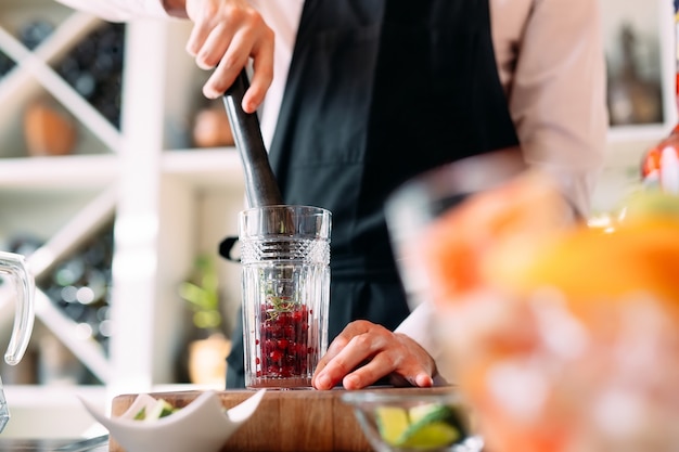 De barman bereidt een bessencocktail op het terras van het restaurant.