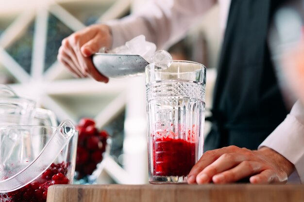 De barman bereidt een bessencocktail op het terras van het restaurant.