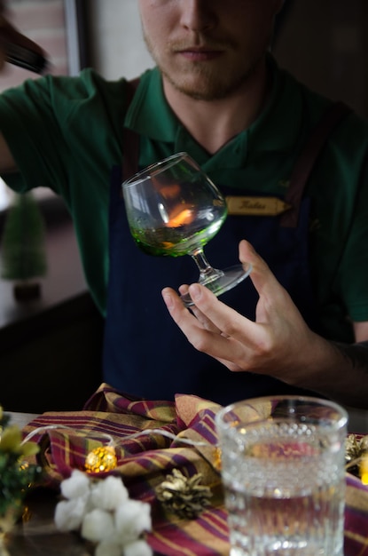 de barman ontsteekt een cocktailvlam van een groene cocktail