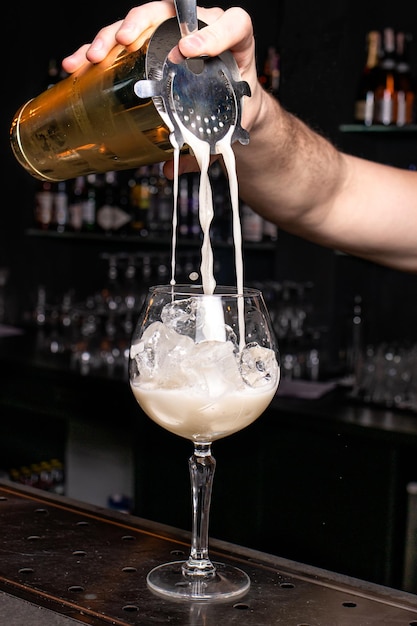 De barman schenkt een schuimende cocktail in het glas