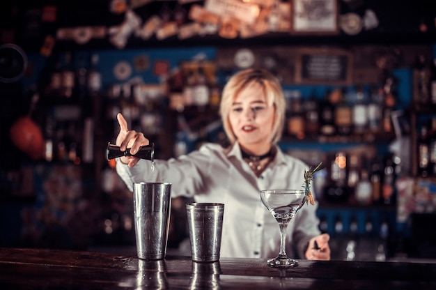 De barman van het meisje maakt een cocktail achter de bar