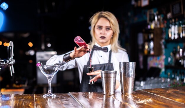 De barman van het meisje maakt een cocktail in het café