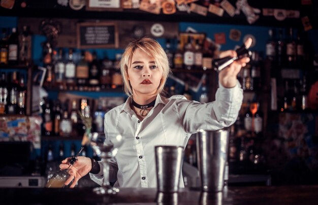 Foto de barman van het meisje maakt een cocktail in het portiershuis