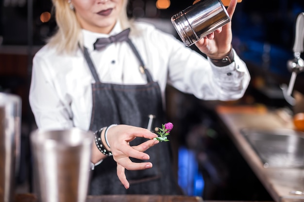 De barman van het meisje maakt een cocktail op het café