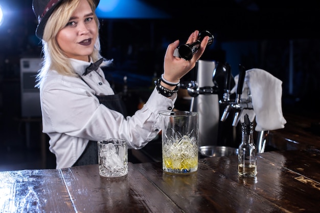 De barman van het meisje mengt een cocktail in de salon