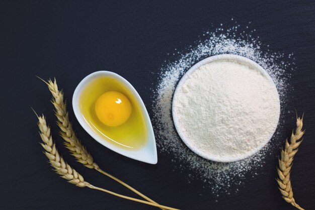 De basis van het voedselconcept van de bloem van bakkerijingrediënten, ei op de zwarte plaat van de leisteen