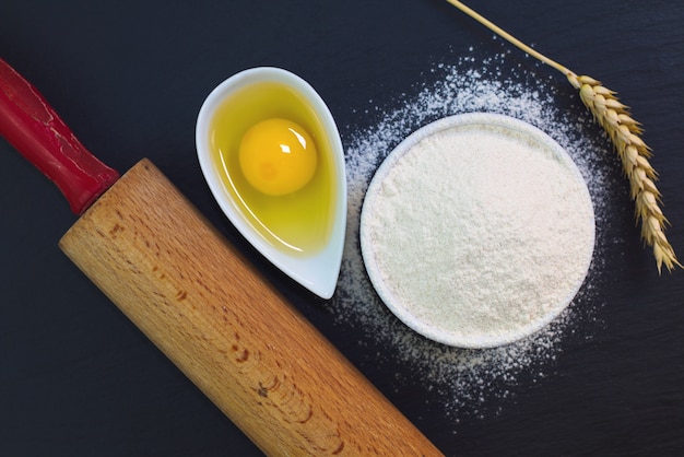 De basis van het voedselconcept van de bloem van bakkerijingrediënten, ei op de zwarte plaat van de leisteen