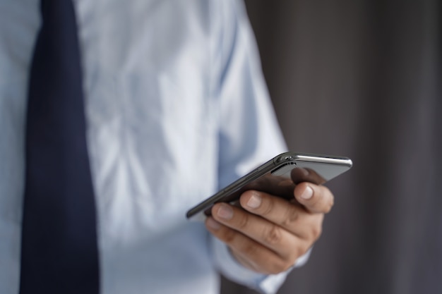 De bedrijfsmens houdt de smartphone op de straat en kopieert ruimte.